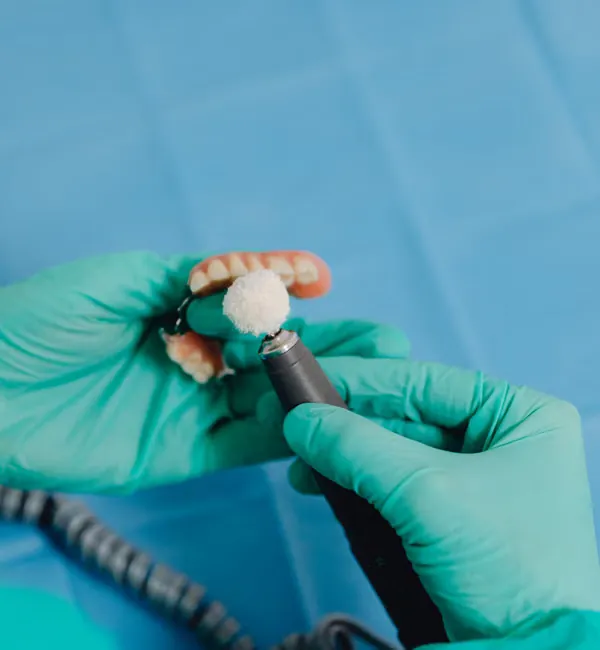 Dental technician polishing complete denture — precision full arch fabrication at Deekshu Dental Bangalore