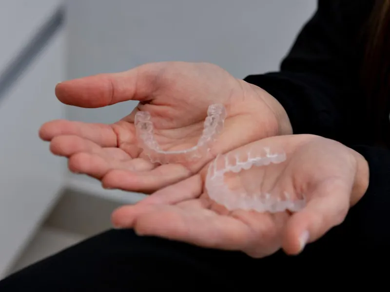 Close-up of clear Invisalign dental aligners held in a dental clinic in Sarjapura, Bangalore — invisible braces treatment